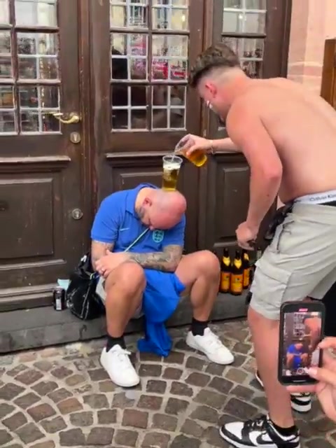 英格蘭球迷在一位睡著的球迷頭上放杯子，并輪番倒啤酒